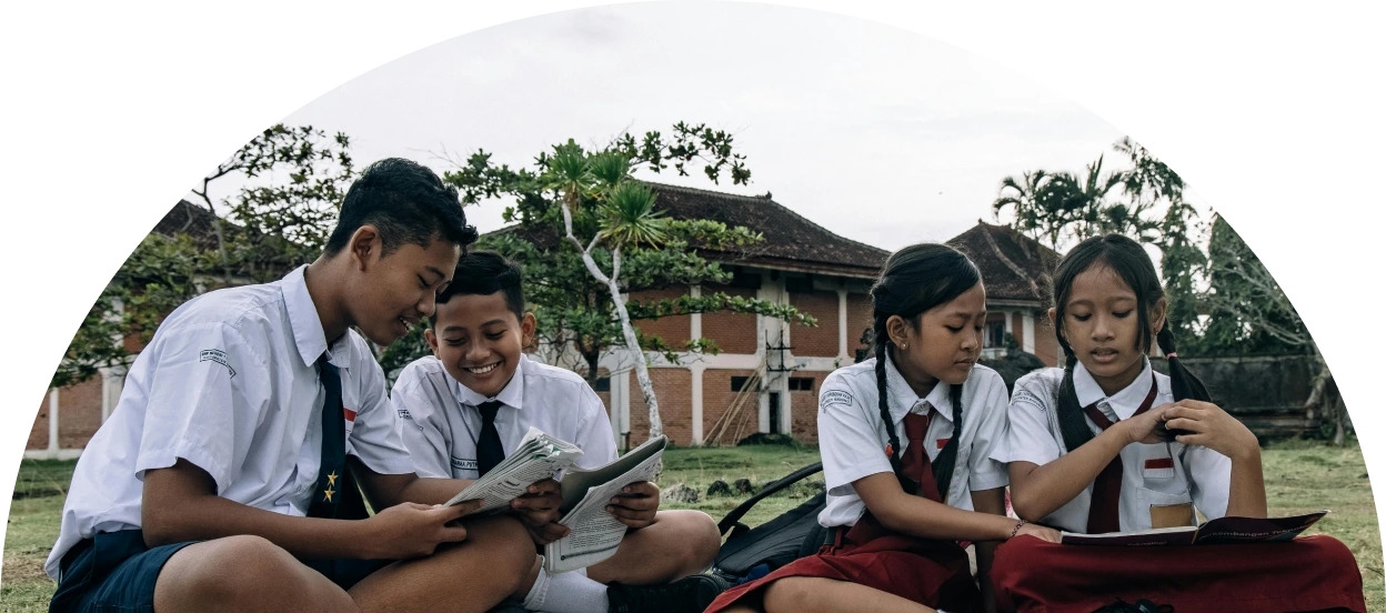 Boys and girls in school uniforms at a picnic holding books